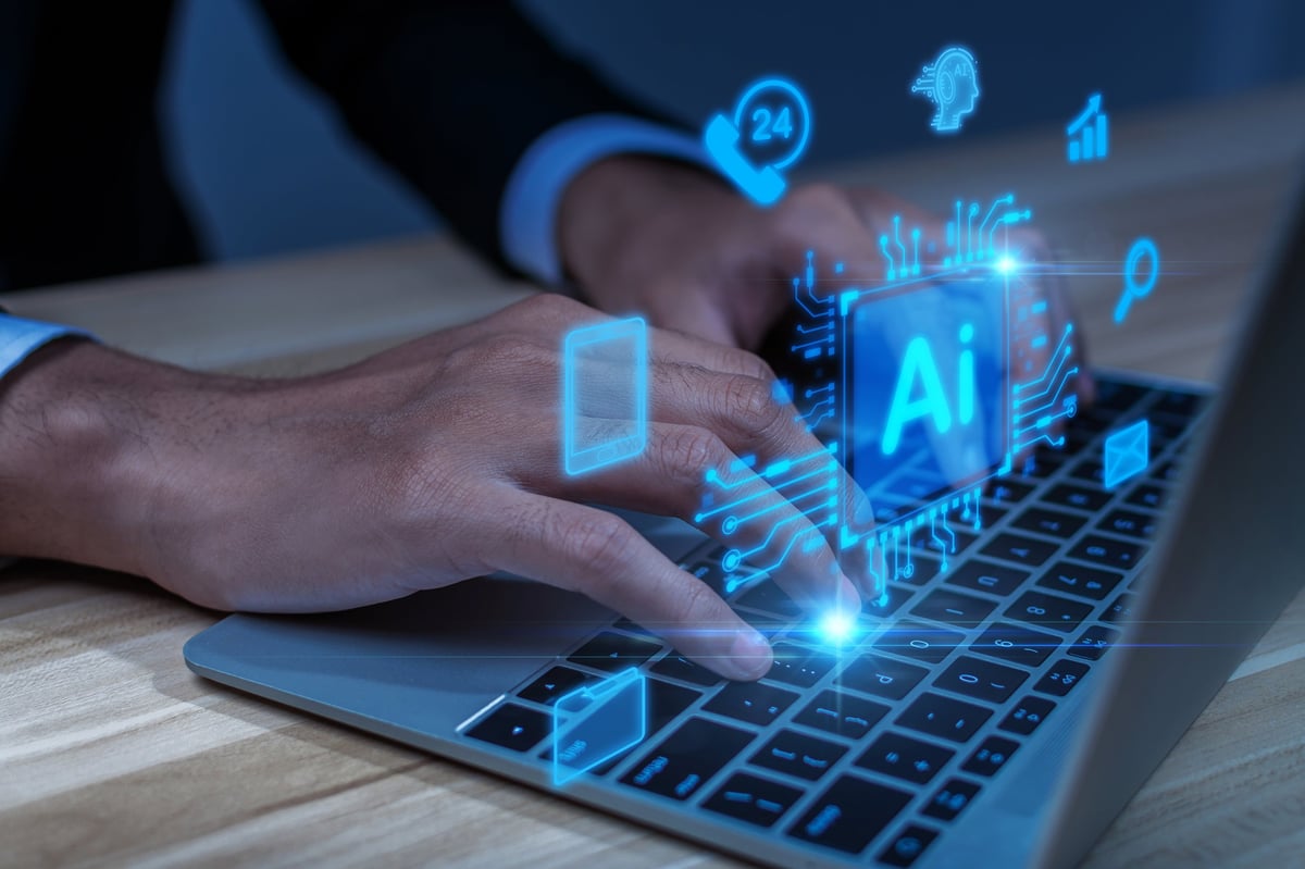hand typing on laptop computer with holographic AI technology icons overlay