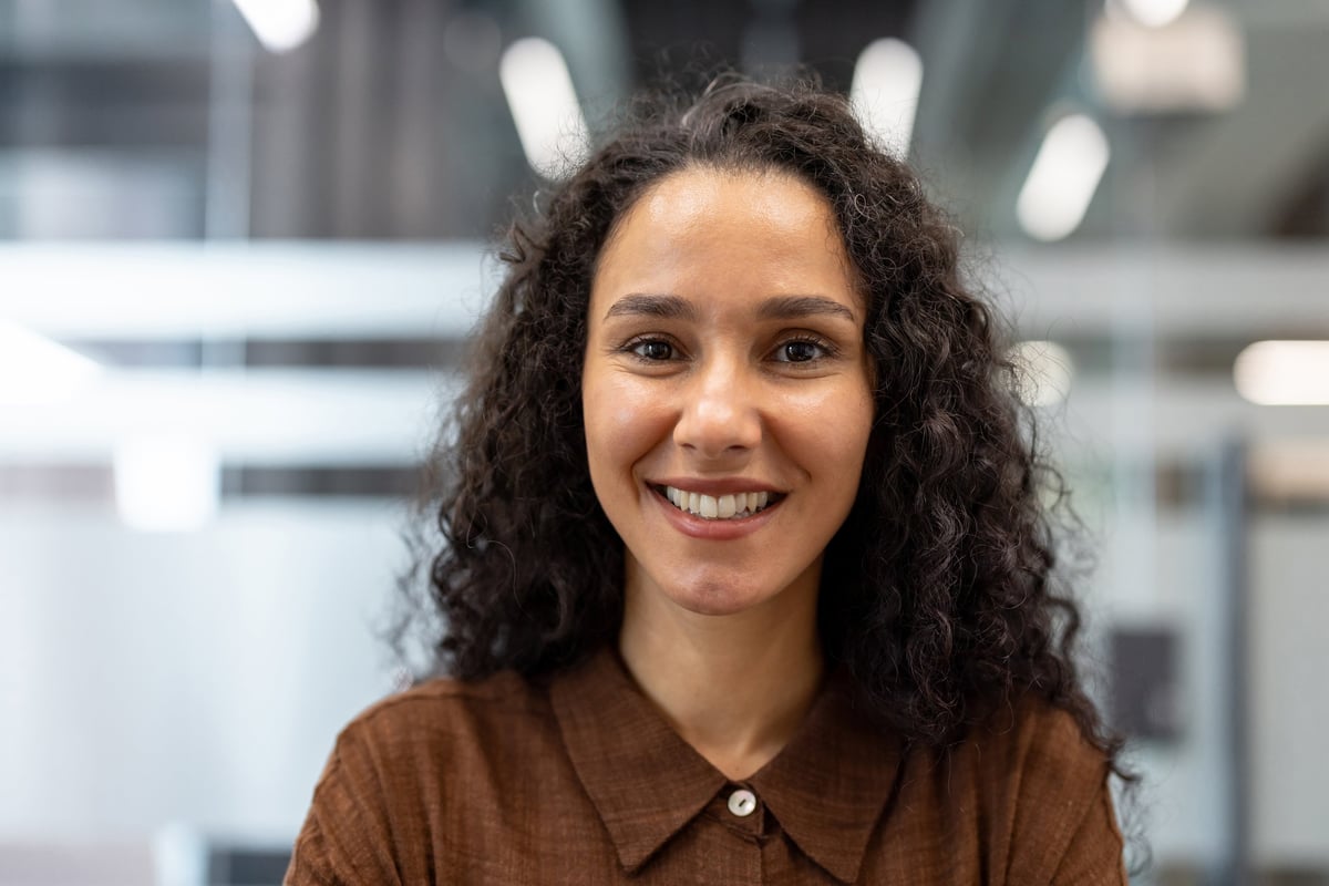 Young curly-haired businesswoman smiling confidently at camera