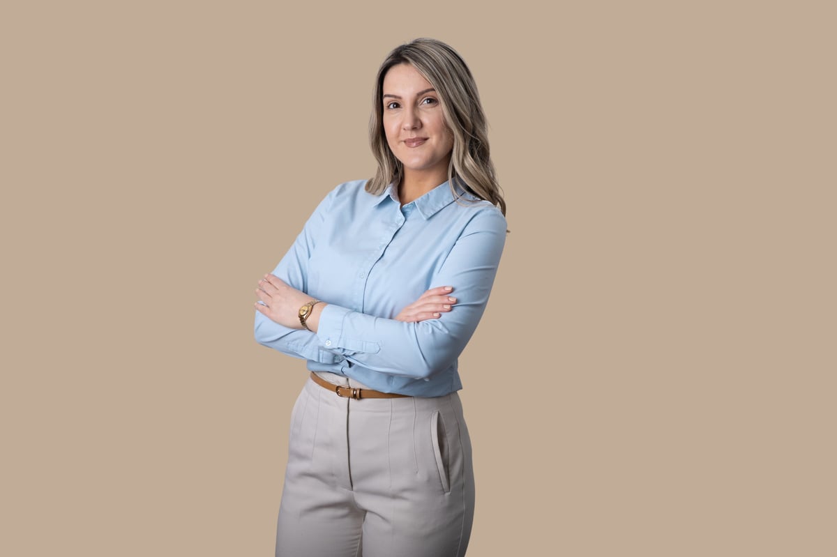Professional woman standing against a solid background, looking at the camera and smiling
